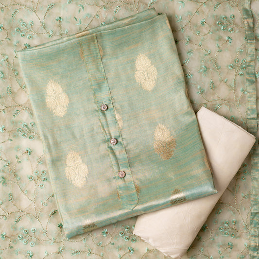 An elegantly crafted Tissue Silk Party wear dress material. A set best suited to gift bride to be or your loved on your anniversary. Tissue silk top with golden color embossed designs, it has show buttons in neck area, also golden color borders in side. Tissue silk dupatta with embroidery work with the same color thread of top and also golden color threads. Cream color cotton silk bottom.
