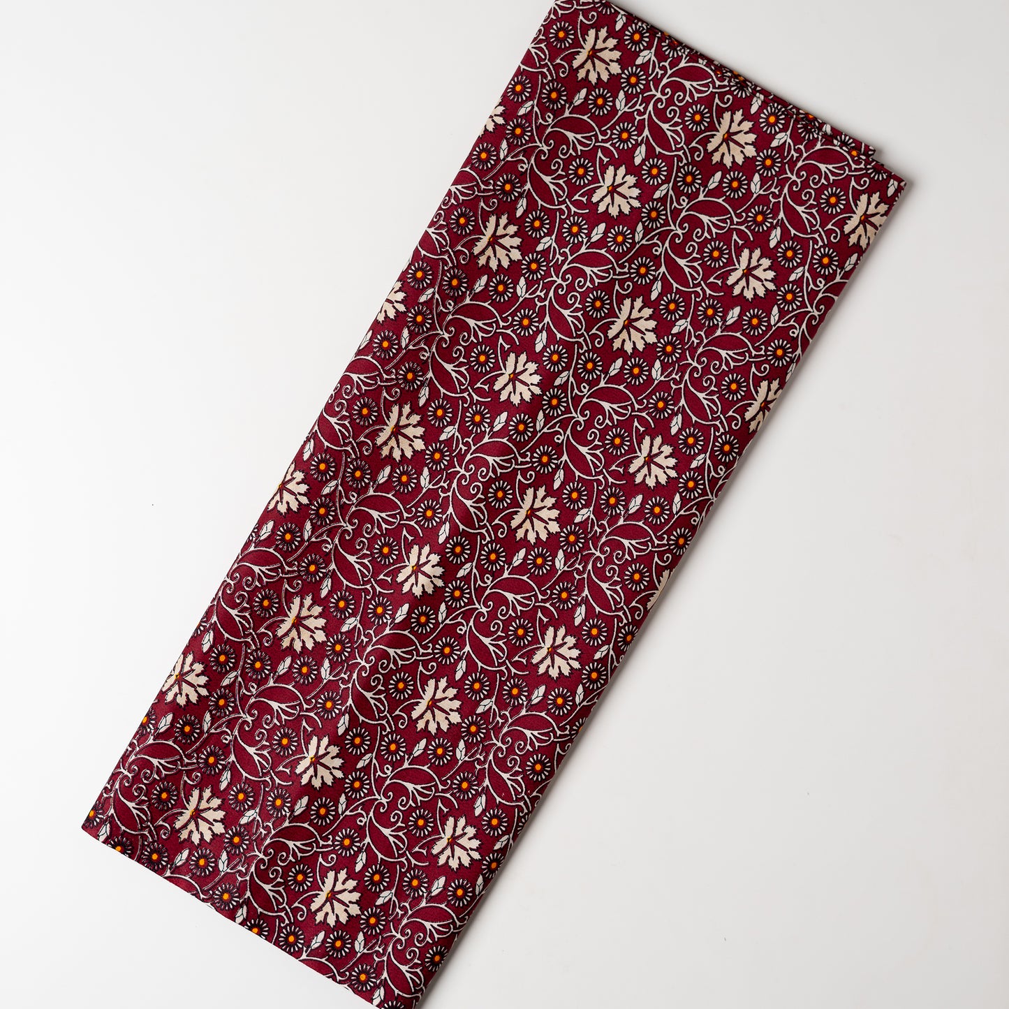 cotton printed fabric in wine red color, it has cream and orange color floral design, small orange dotted design