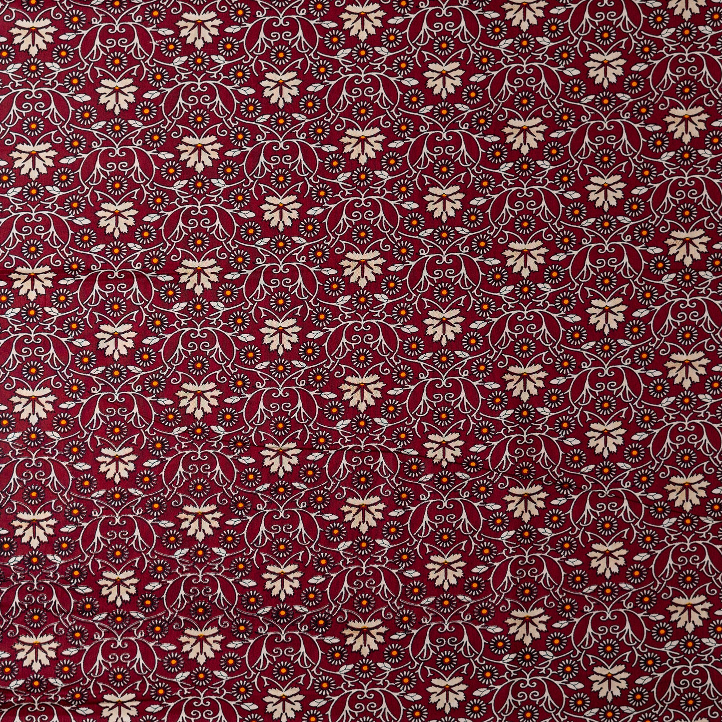 cotton printed fabric in wine red color, it has cream and orange color floral design, small orange dotted design