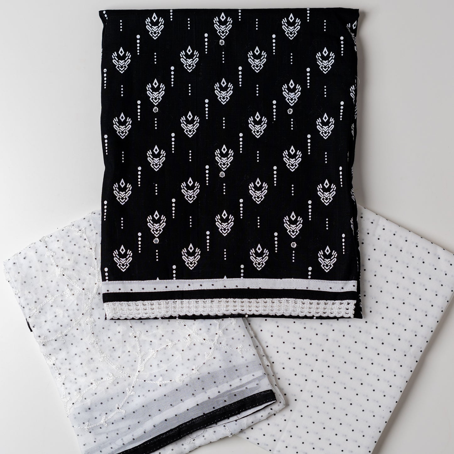 Cotton dress material with beautiful print design in white color on top, mirror work. It has white color lace on the borders. Chiffon dupatta with embroidery work in white color and black dotted prints. Cotton white color bottom with black dots.
