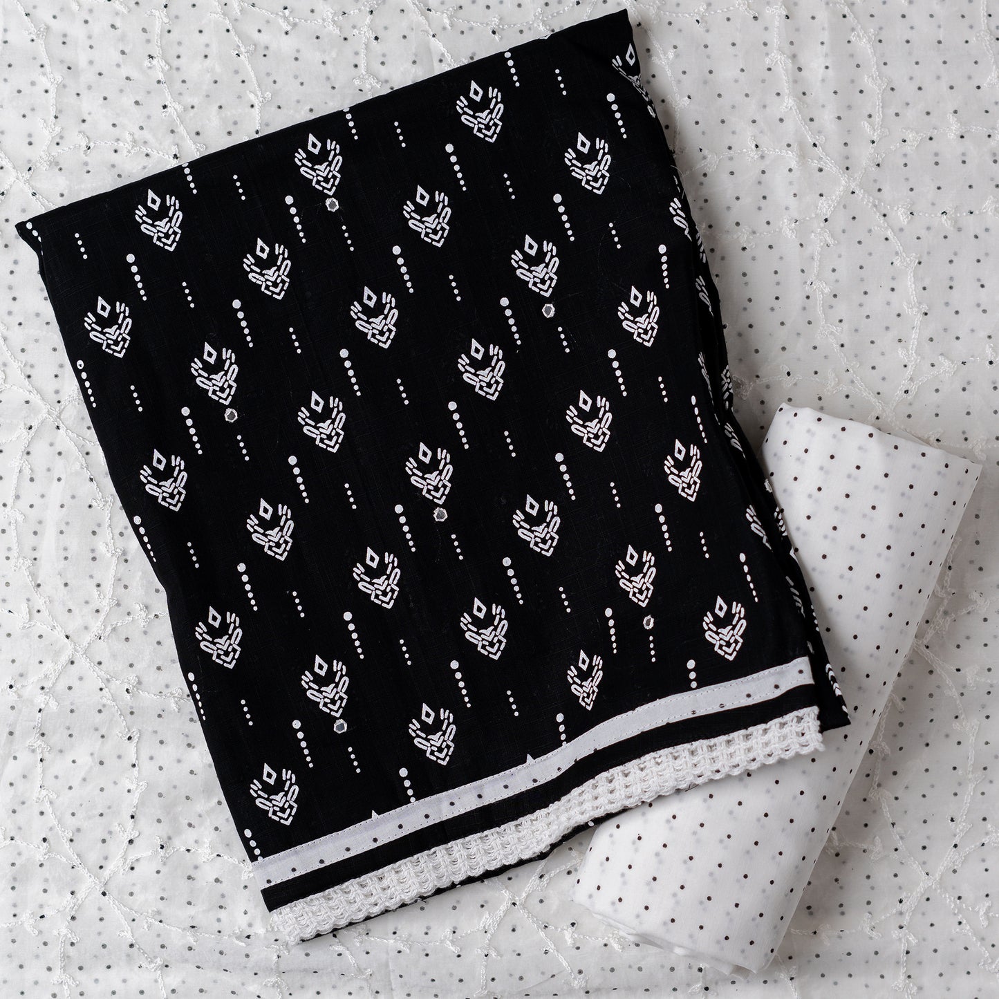 Cotton dress material with beautiful print design in white color on top, mirror work. It has white color lace on the borders. Chiffon dupatta with embroidery work in white color and black dotted prints. Cotton white color bottom with black dots.