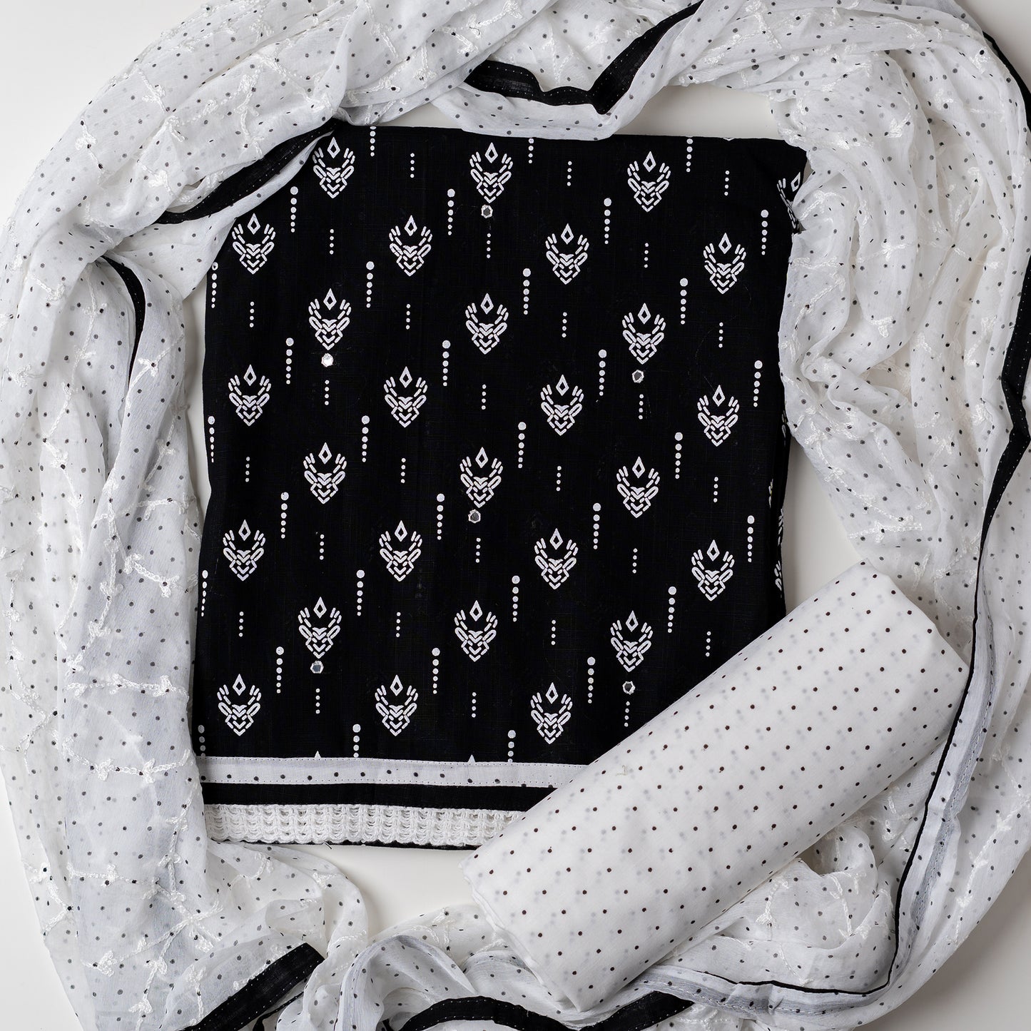Cotton dress material with beautiful print design in white color on top, mirror work. It has white color lace on the borders. Chiffon dupatta with embroidery work in white color and black dotted prints. Cotton white color bottom with black dots.