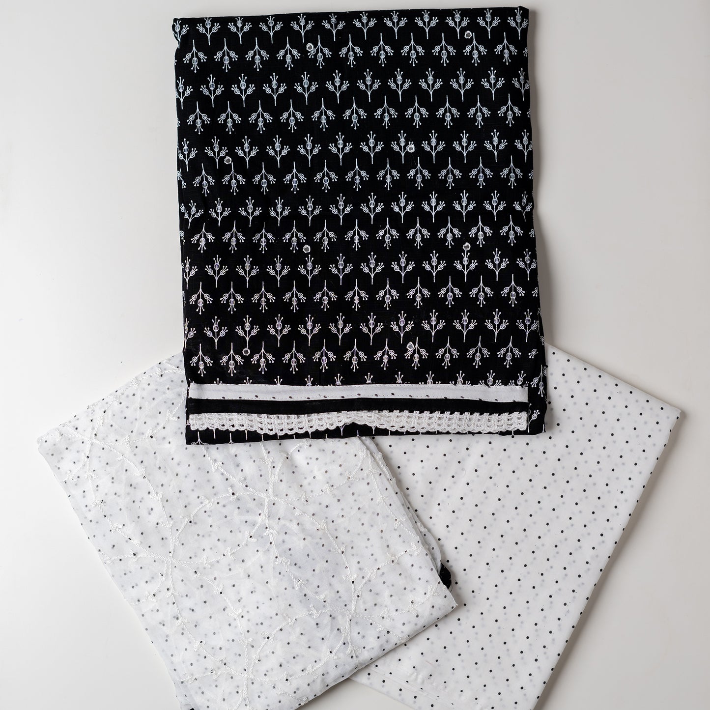 Cotton black color dress material with beautiful print design in white color on top, mirror work. It has white color lace on the borders. Chiffon dupatta with embroidery work in white color and black dotted prints. Cotton white color bottom with black dots.