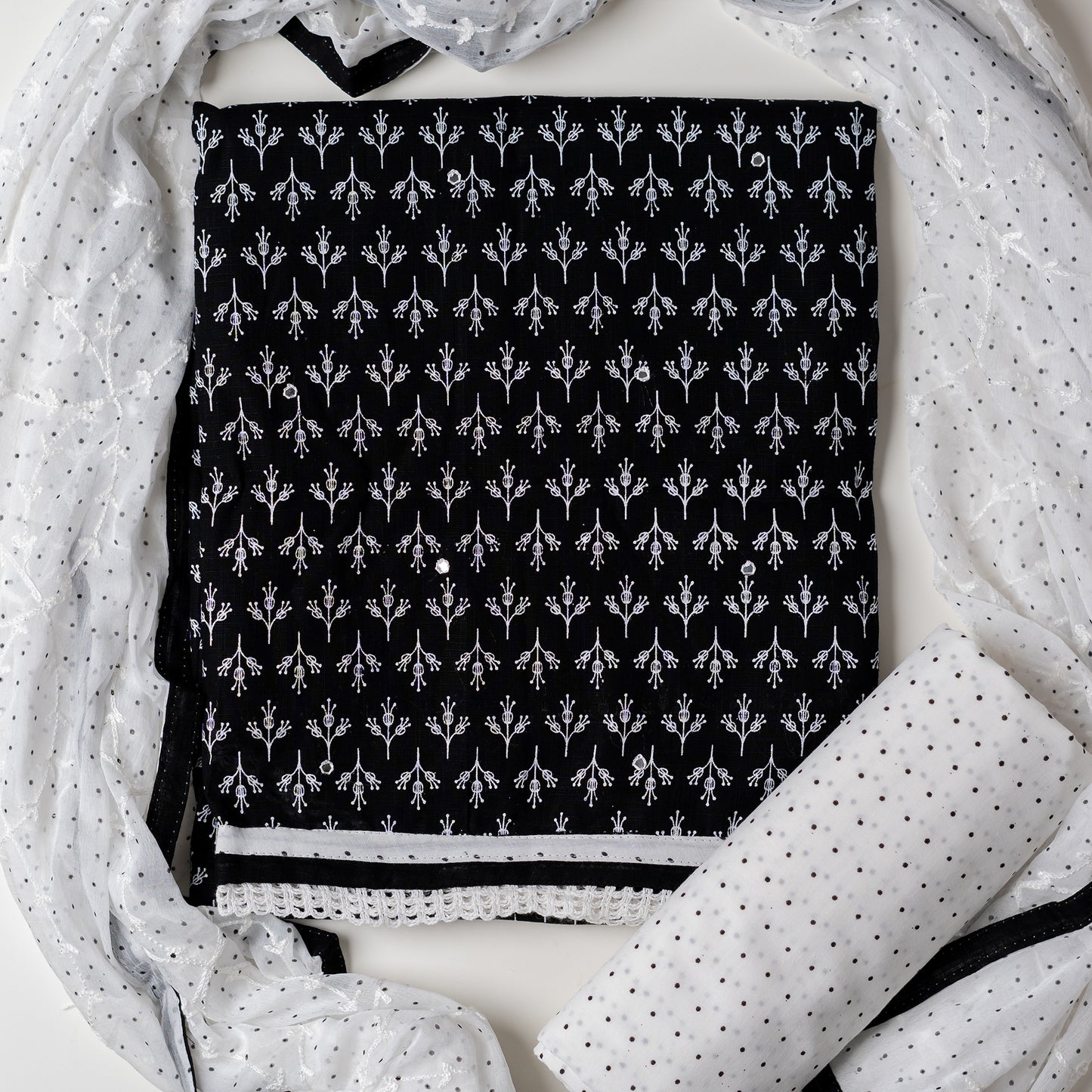 Cotton black color dress material with beautiful print design in white color on top, mirror work. It has white color lace on the borders. Chiffon dupatta with embroidery work in white color and black dotted prints. Cotton white color bottom with black dots.