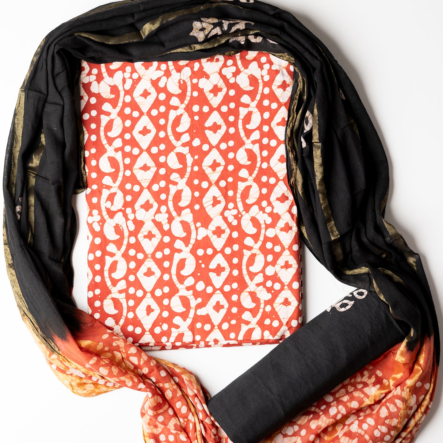 Orange color cotton wax batik printed dress material top, black cotton bottom with prints. Cotton dupatta with golden color lines and wax batik prints.