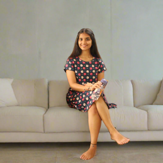 cotton navy blue color short night gown with floral print design all over, picture of model sitting in a sofa comfortably