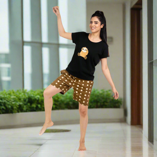 Woman in black t-shirt with a graphic and brown shorts with white polka dots, posing in an indoor setting.