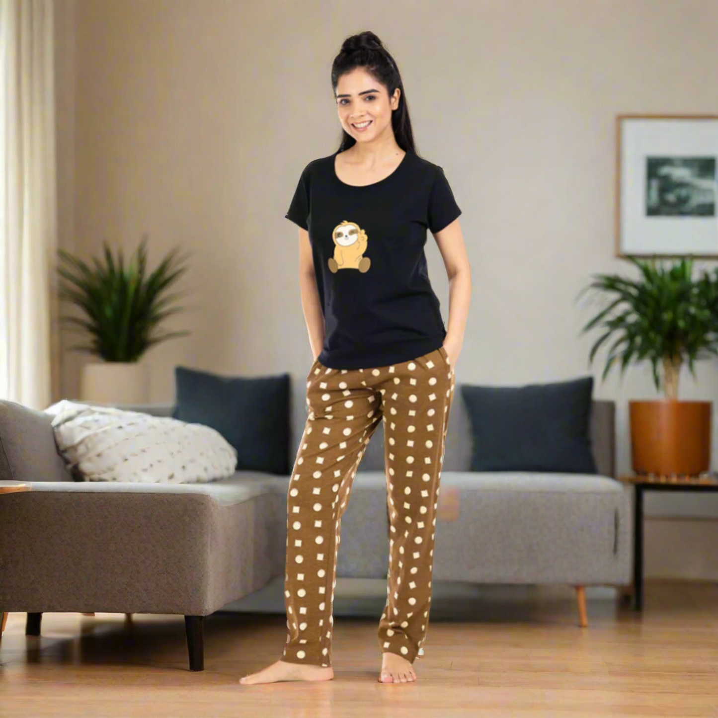 A woman standing and posing in a black t-shirt and brown pajama set with a geometric pattern.