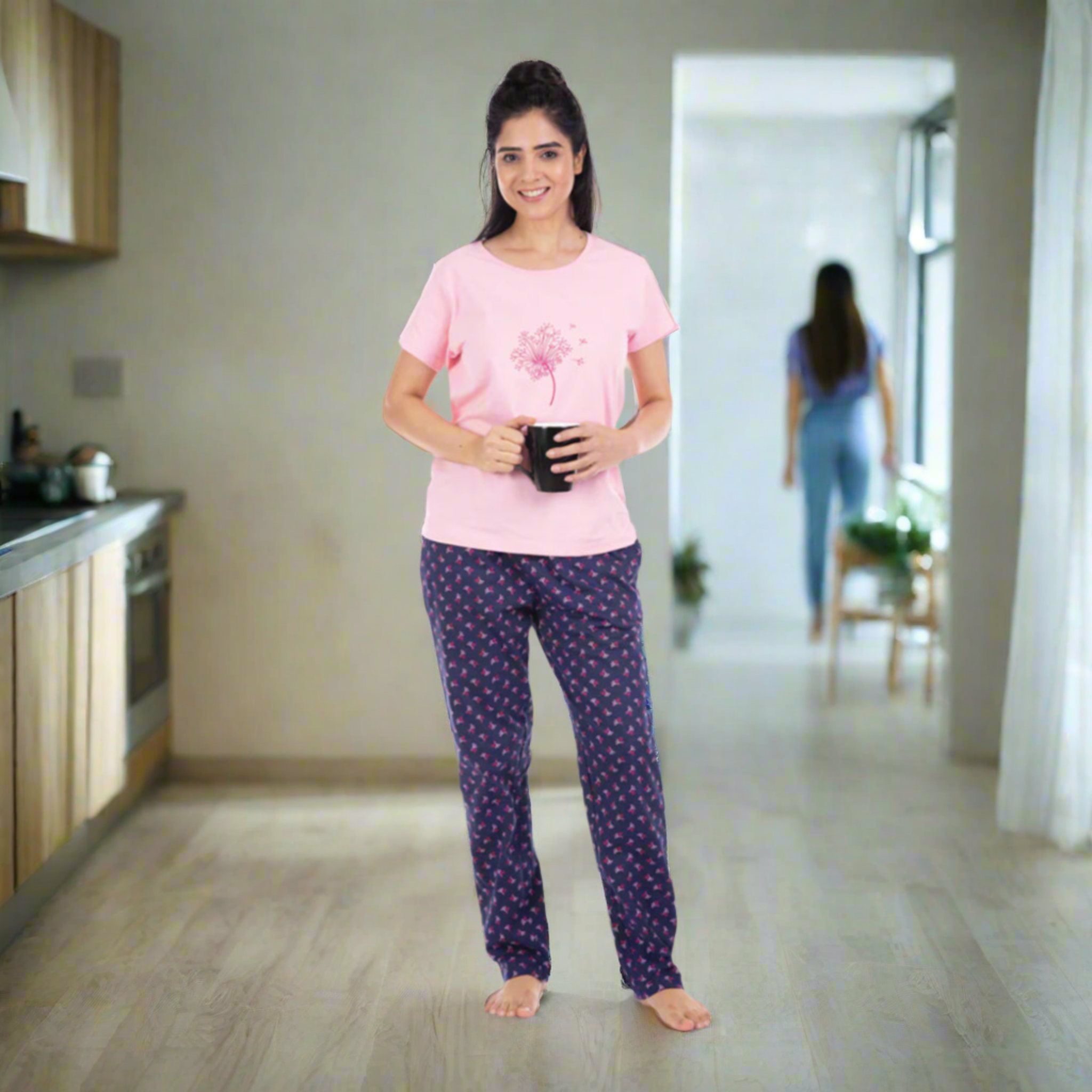 Women wearing pink t shirt with design, navy blue pyjama with pritns, holding a coffee mug in hand