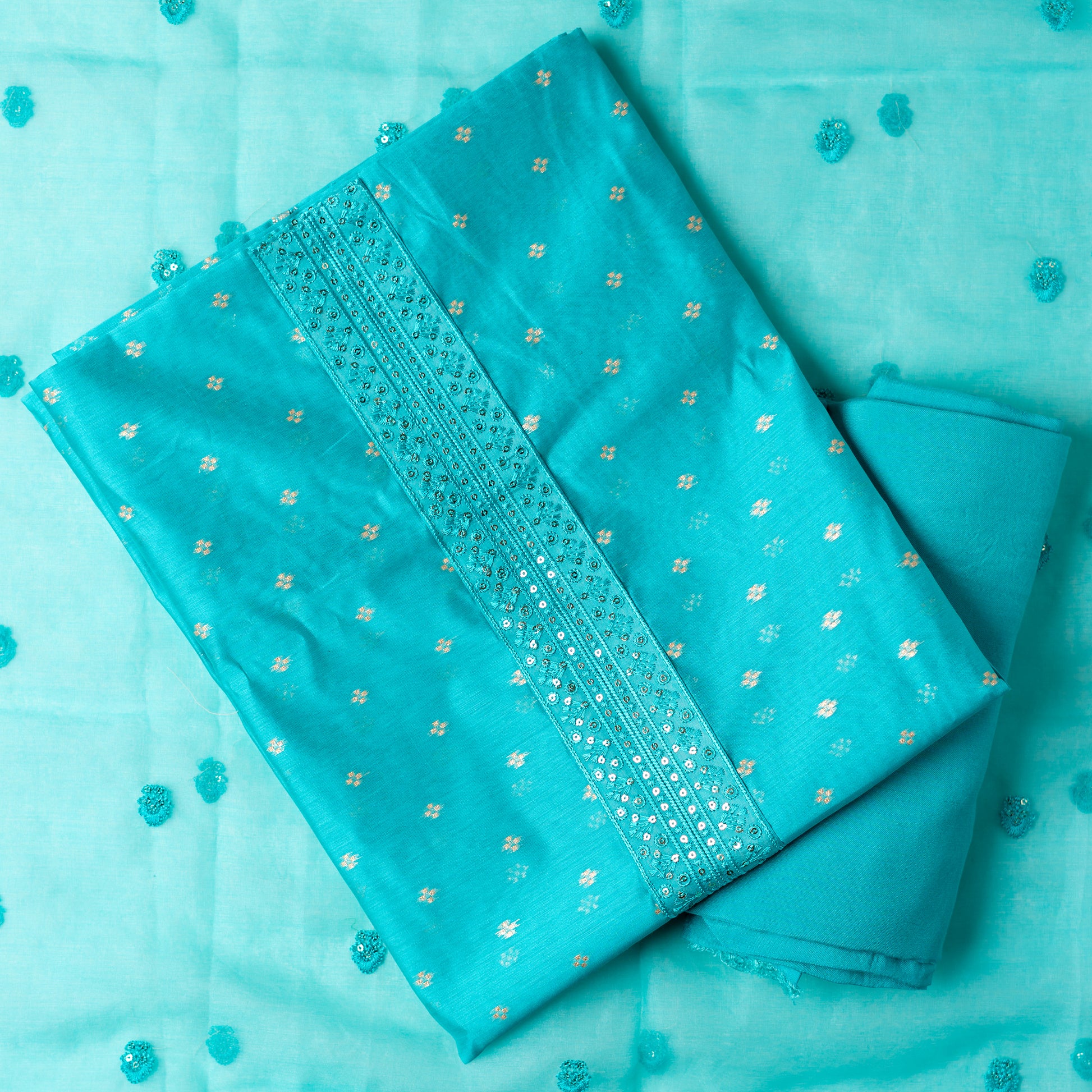Beautiful turquoise color chanderi silk dress material with embroidery and sequins work on neck line. It has jacquard weaving in golden threads all over the top. Tissue silk dupatta with elegant embroidery and sequins work all over dupatta and at the borders. Turquoise color cotton silk bottom  matching the top and dupatta.