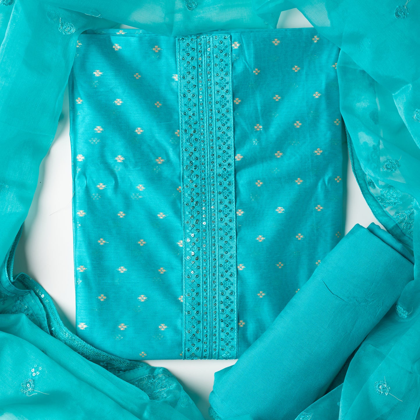Beautiful turquoise color chanderi silk dress material with embroidery and sequins work on neck line. It has jacquard weaving in golden threads all over the top. Tissue silk dupatta with elegant embroidery and sequins work all over dupatta and at the borders. Turquoise color cotton silk bottom  matching the top and dupatta.