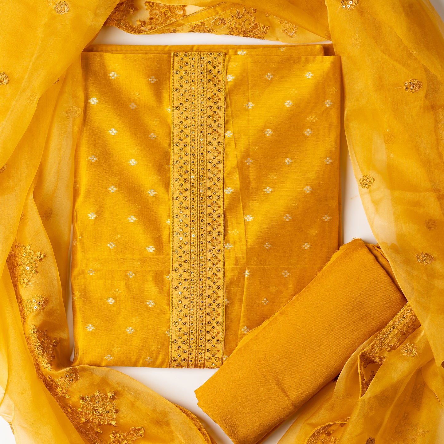 golden yellow color Beautiful chanderi silk dress material with embroidery and sequins work on neck line. It has jacquard weaving in golden threads all over the top. Tissue silk dupatta with elegant embroidery and sequins work all over dupatta and at the borders. Golden Yellow color cotton silk bottom  matching the top and dupatta.