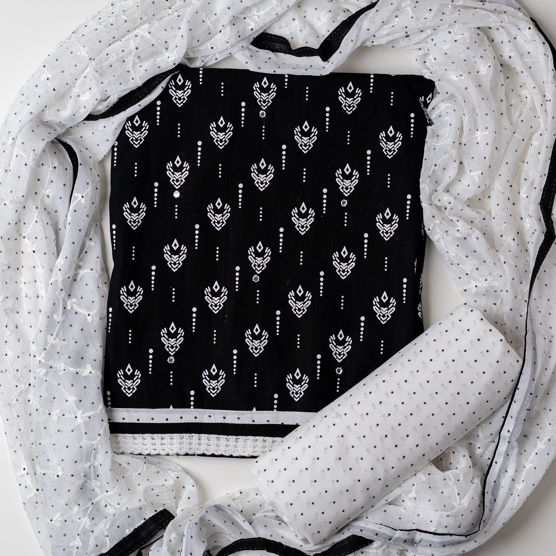 Cotton dress material with beautiful print design in white color on top, mirror work. It has white color lace on the borders. Chiffon dupatta with embroidery work in white color and black dotted prints. Cotton white color bottom with black dots.