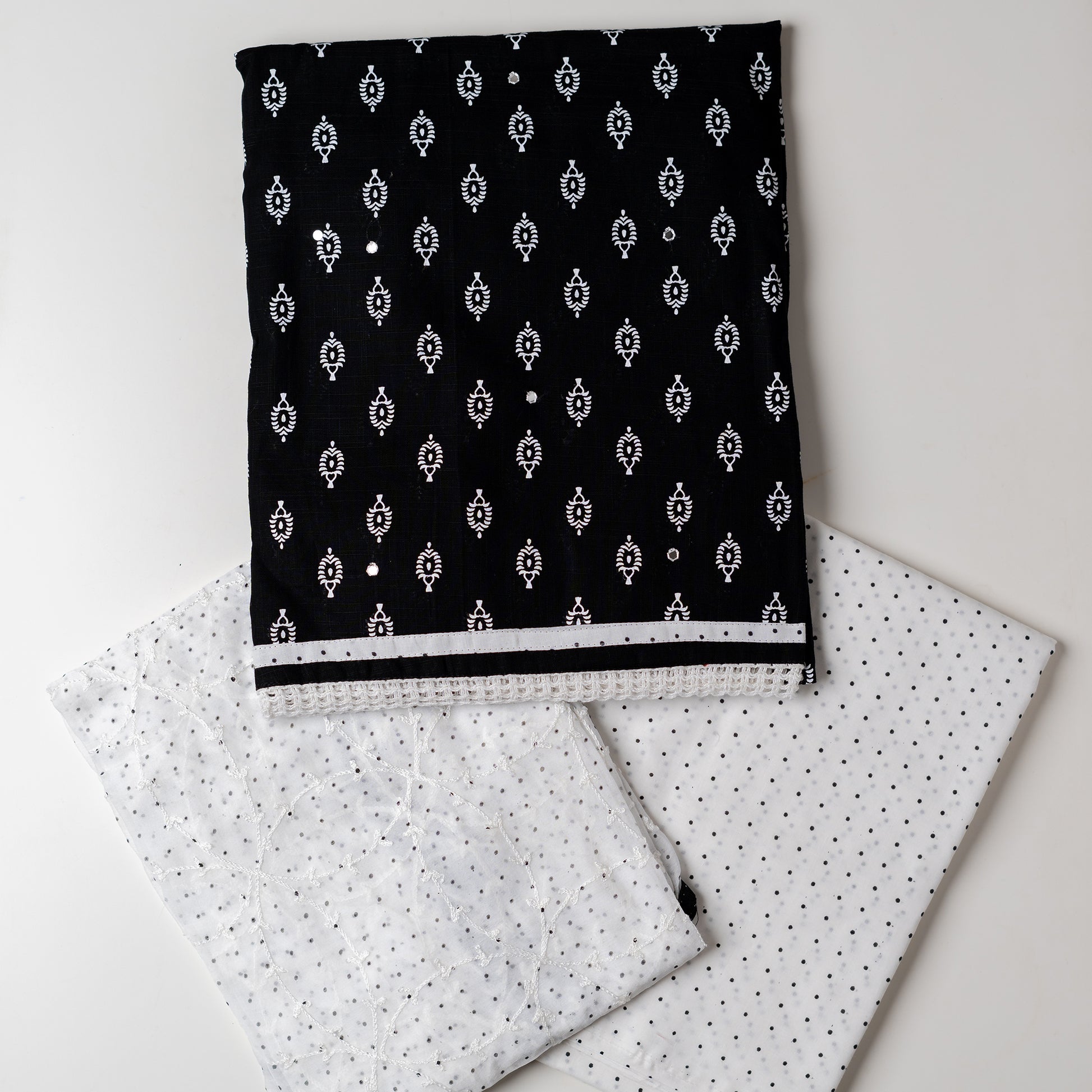 Cotton black color dress material with beautiful print design in white color on top, mirror work. It has white color lace on the borders. Chiffon dupatta with embroidery work in white color and black dotted prints. Cotton white color bottom with black dots.