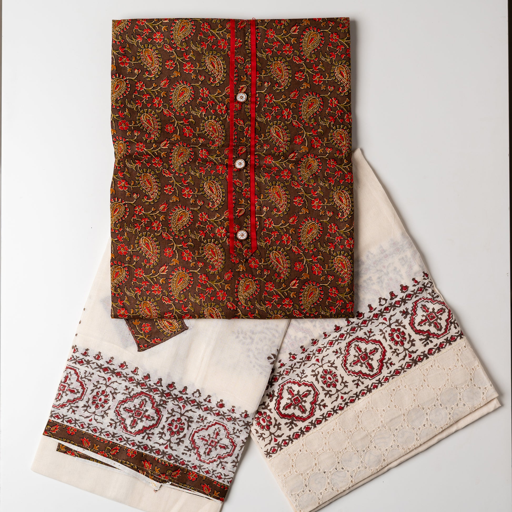 Salwar suit set, Cotton top with brown color base and multi color print design, buttons and contrast color piping in yoke, cream color cotton bottom with hakoba design at the edges and print. Cotton dupatta with matching color prints and cut works