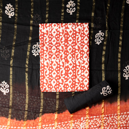 Orange color cotton wax batik printed dress material top, black cotton bottom with prints. Cotton dupatta with golden color lines and wax batik prints.