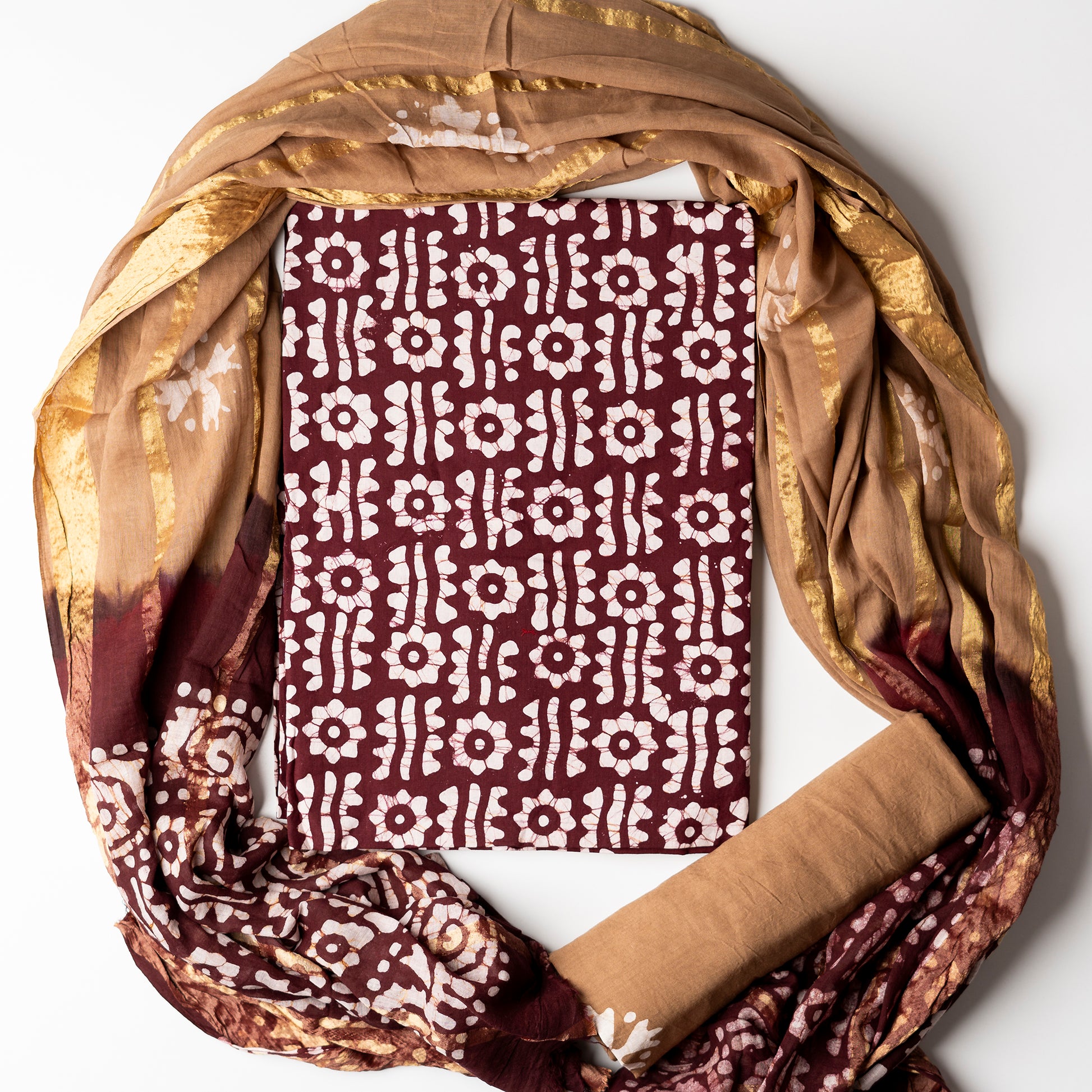 Brown color cotton wax batik printed dress material top, light brown color cotton bottom with prints. Cotton dupatta with golden color lines and wax batik prints.