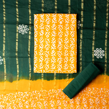Yellow color cotton wax batik dress material with white prints, cotton green color bottom with batik prints. Cotton green and yellow color dupatta with golden color lines in between and wax batik prints