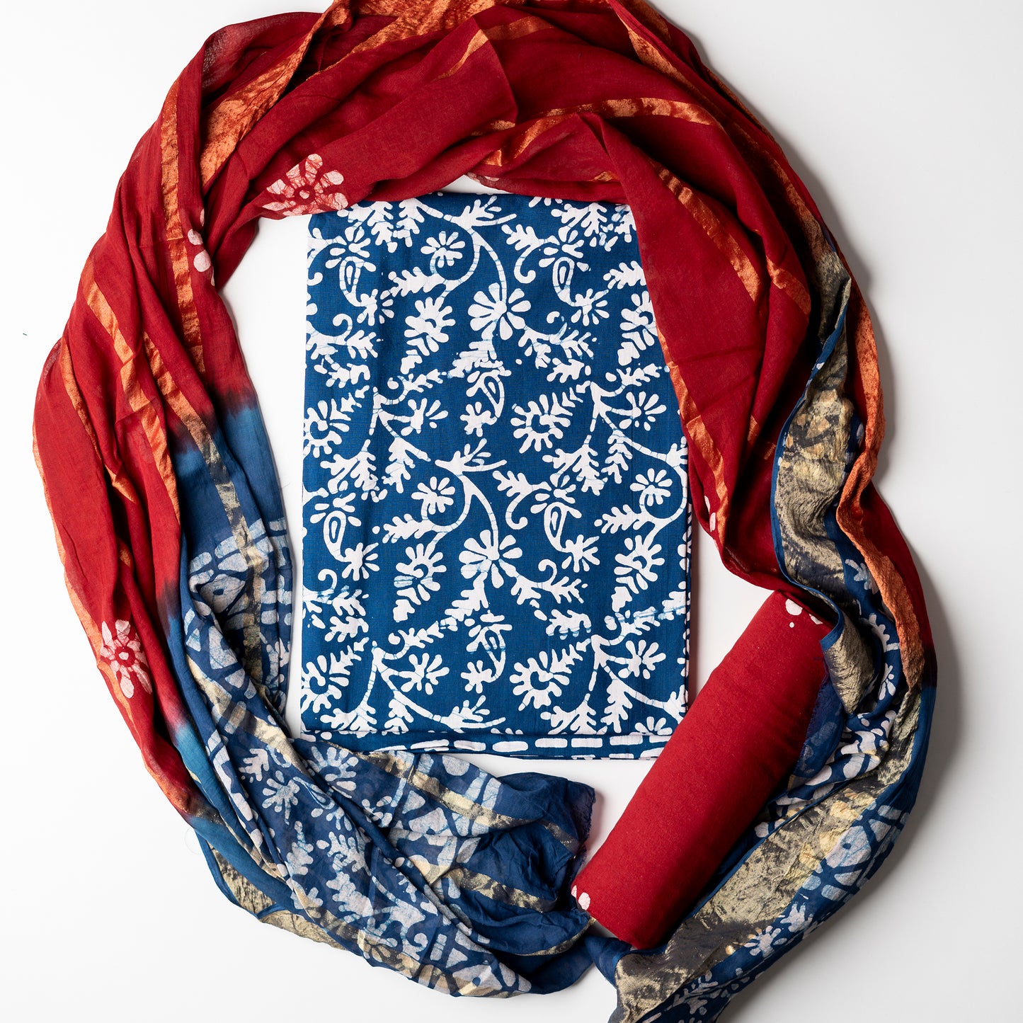 It's a good color combination, fresh and cool blue with red. Cotton blue color wax batik dress material with white prints. Red color cotton bottom with wax prints. Red and blue color cotton dupatta with golden color lines in between and also wax batik prints