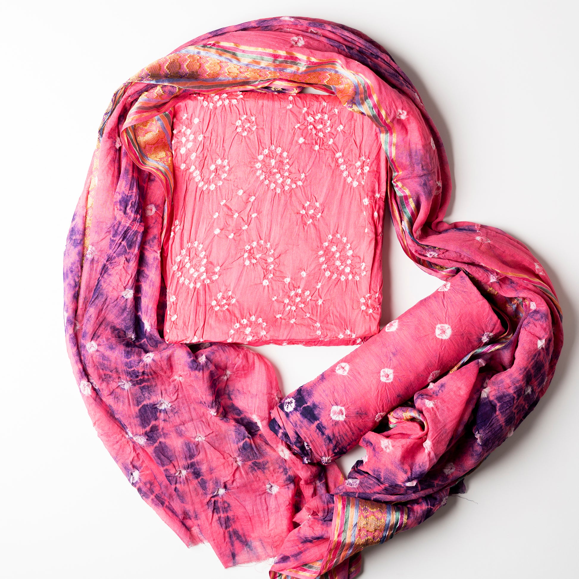 Pink color top with white bandhej designs,  Pink color bottom with shibori designs in blue. Pink color dupatta with shibori designs in blue color and golden borders.