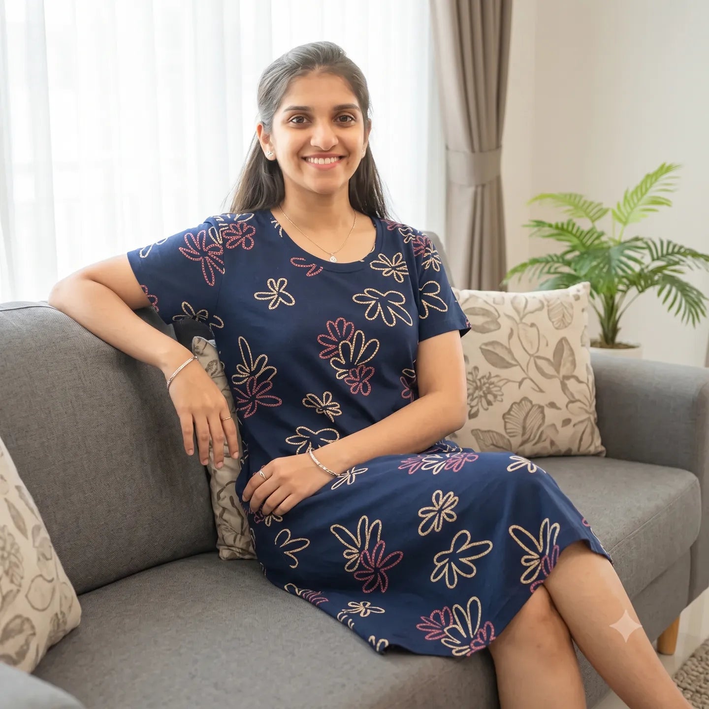 women wearing navy blue color cotton knee length short nighty and sitting in a living room sofa 