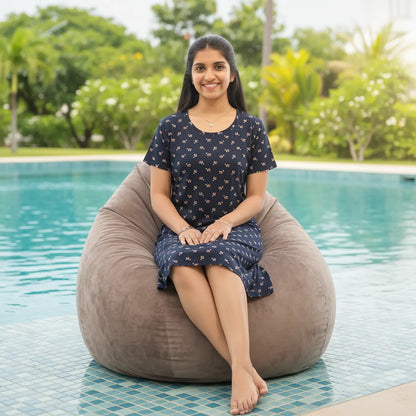 women sitting in a bean bag in front of a resort swimming pool wearing a navy blue color cotton short nighty with all over print design.