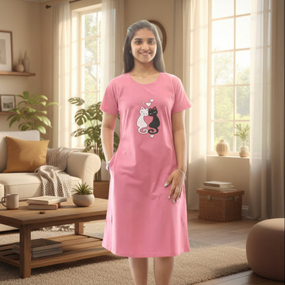 Woman wearing a pink knee length short nighty with a black and white cat design