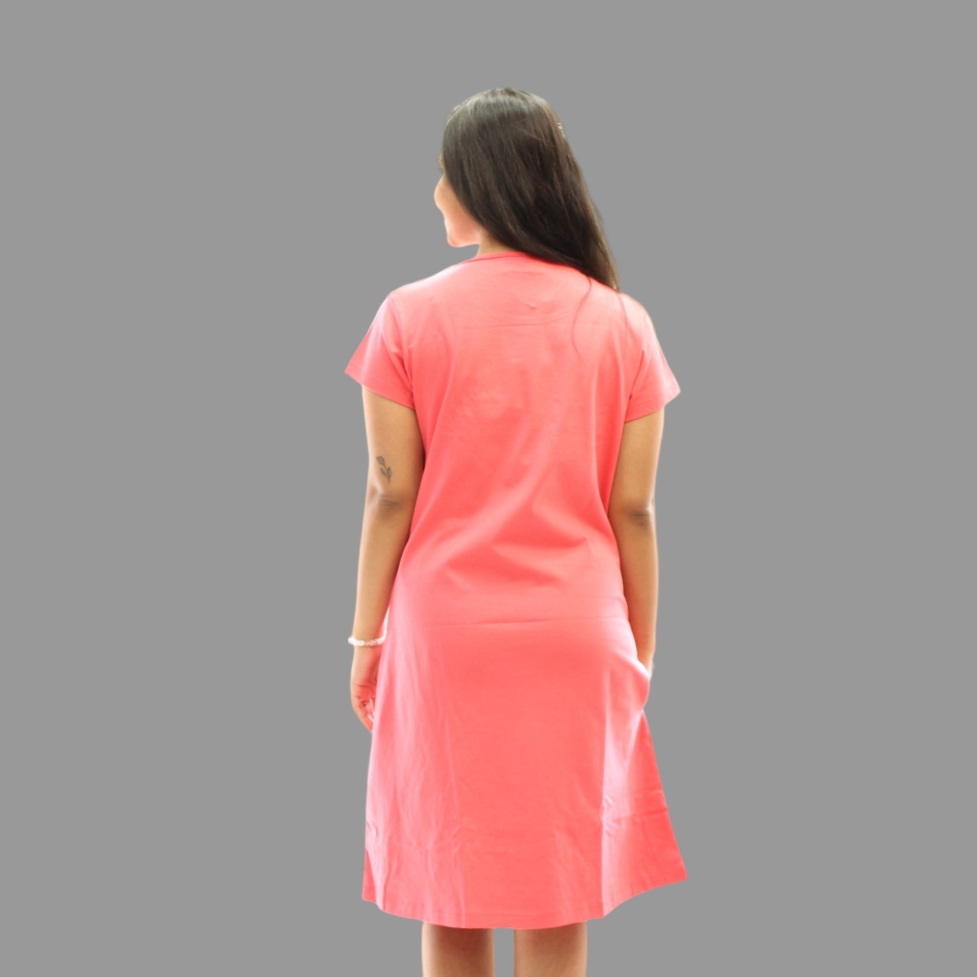 women wearing coral color plain short nighty and standing showing the backside view 