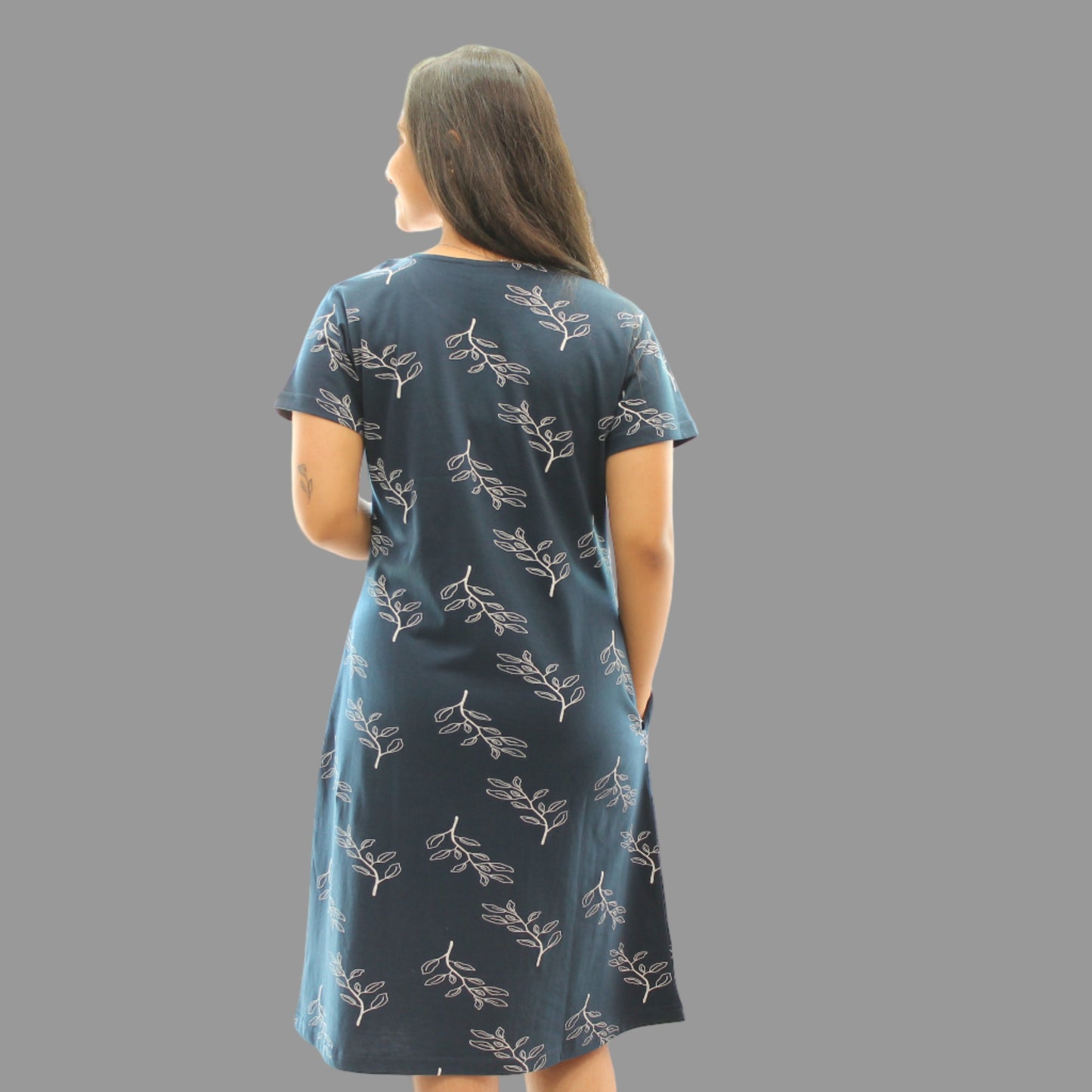 women standing backwards wearing navy blue color cotton short nighty with leaves design printed in white 