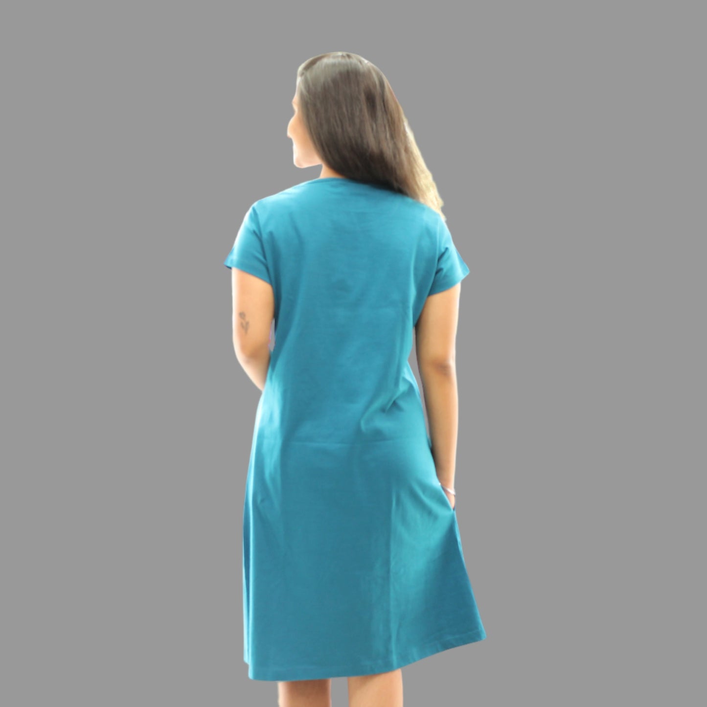 women wearing teal color short nighty, standing backwards with view of the backside , hands in pocket