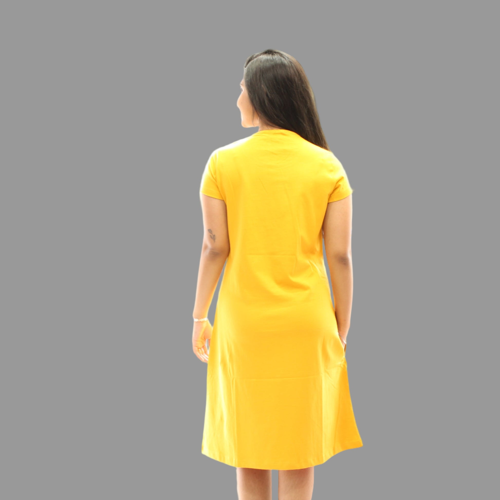 women standing backwards wearing an yellow color short nighty 