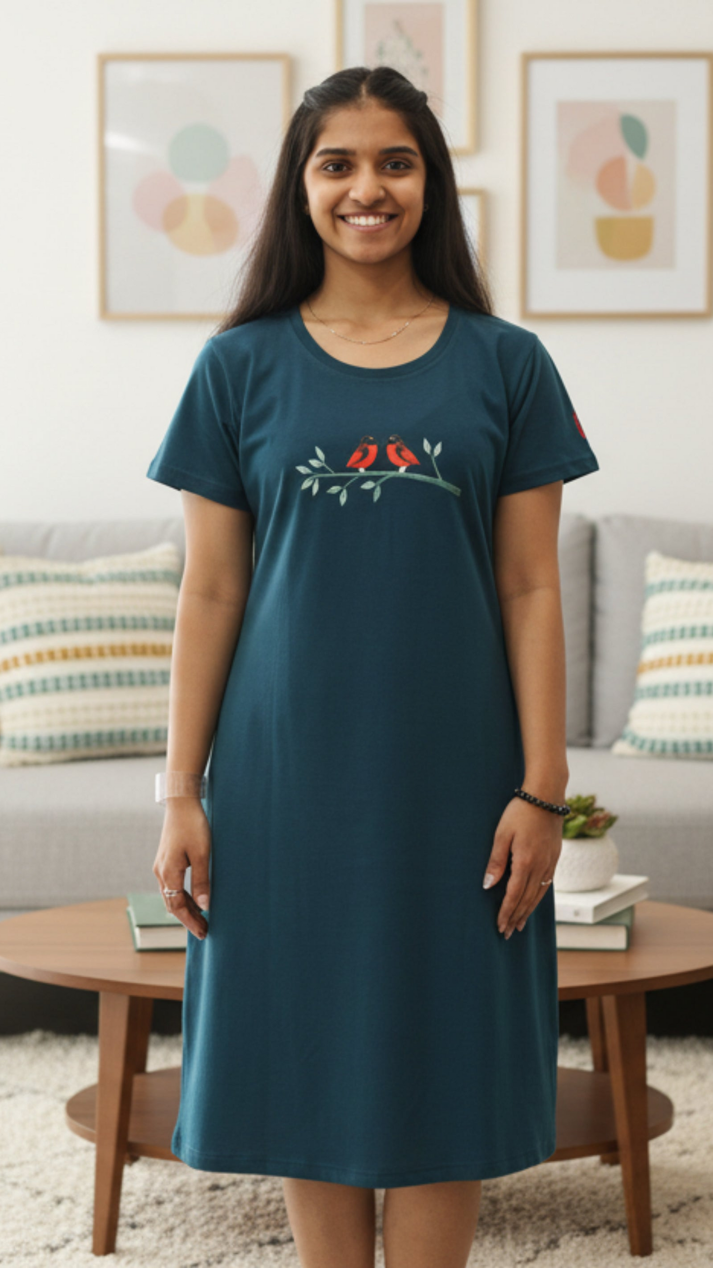 Woman wearing a teal dress with a red bird design in a living room.