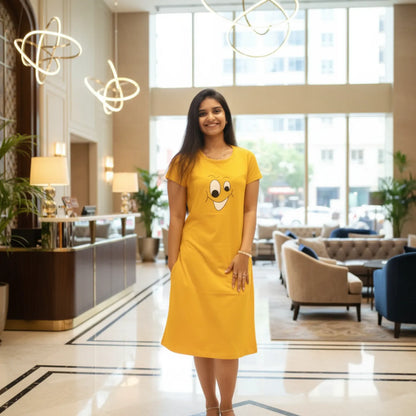 Woman in a yellow dress with a smiley face design standing in a modern hotel lobby.