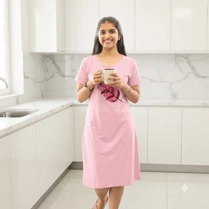 women wearing a light pink hosiery cotton knee length short nighty and standing in a modern kitchen holding a coffee mug