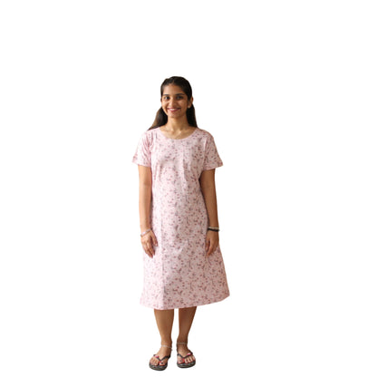women wearing printed knee length light pink dress , standing in a room with white background