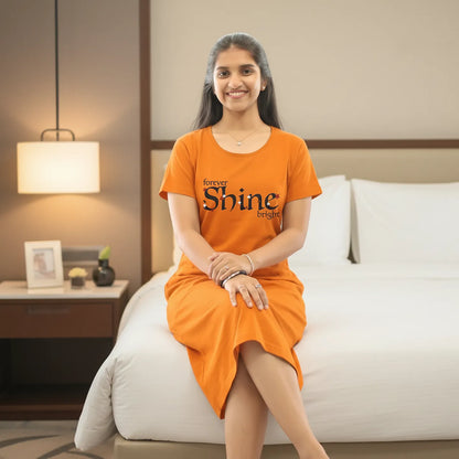 women wearing a dark orange color cotton knee length short nighty and sitting on the edge of bed
